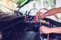 Car mechanic is holding a wrench ready to check the engine and maintenance with blurry voltmeter for check voltage level in Royalty Free Stock Photo