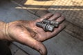A car mechanic holds in his open, dirty hand metal screws for screwing aluminum and steel rims.