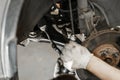 Car mechanic inspecting car wheel and repair suspension detail. Lifted automobile at repair service station. replacement Royalty Free Stock Photo