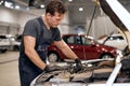 Car mechanic looking inside of engine in garage. Car motor repair. Problems and solutions