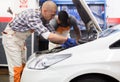 Car mechanic looking at open car hood for internal checking