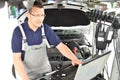 Car mechanic maintains a vehicle with the help of a diagnostic computer - modern technology in the car repair shop Royalty Free Stock Photo