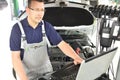 car mechanic maintains a vehicle with the help of a diagnostic computer - modern technology in the car repair shop Royalty Free Stock Photo