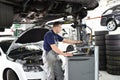 car mechanic maintains a vehicle with the help of a diagnostic computer - modern technology in the car repair shop Royalty Free Stock Photo