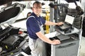 car mechanic maintains a vehicle with the help of a diagnostic computer - modern technology in the car repair shop Royalty Free Stock Photo