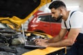 Car mechanic maintains vehicle using diagnostic laptop computer for checking engine problems Royalty Free Stock Photo