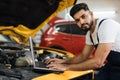 Car mechanic maintains vehicle using diagnostic laptop computer for checking engine problems Royalty Free Stock Photo