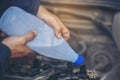 Car Mechanic man hands pouring Deionized purified Distilled water for car battery mechanical service. Close up hands man hold