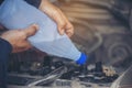 Car Mechanic man hands pouring Deionized purified Distilled water for car battery mechanical service. Close up hands man hold