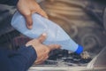 Car Mechanic man hands pouring Deionized purified Distilled water for car battery mechanical service. Close up hands man hold