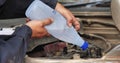 Car Mechanic man hands pouring Deionized purified Distilled water for car battery mechanical service. Close up hands man hold