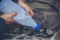 Car Mechanic man hands pouring Deionized purified Distilled water for car battery mechanical service. Close up hands man hold