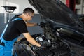 Car mechanic noting repair parts during open car hood engine repair at garage. Mechanic man open a car hood and check up