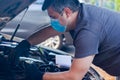 Car mechanic on protective mask fixing car engine, auto mechanic is repairing car engine