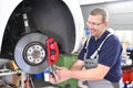 Car mechanic repairs brakes of a vehicle on the lifting platform in a workshop Royalty Free Stock Photo