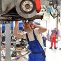 Car mechanic repairs vehicle in a workshop