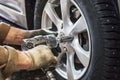 Car mechanic replace car wheels of lifted automobile by pneumatic wrench at repair service shop garage station Royalty Free Stock Photo