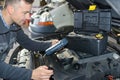 Car mechanic replacing oil on engine in garage