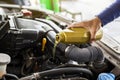 Car mechanic replacing and pouring fresh oil into engine at maintenance repair service station Royalty Free Stock Photo