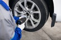 Car mechanic screwing or unscrewing wheel of lifted automobile by pneumatic wrench at repair service station Royalty Free Stock Photo