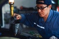 Car mechanic in uniform at garage and car service station performing engine oil checking and filling up Royalty Free Stock Photo