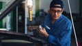 Car mechanic in uniform at garage and car service station performing engine oil checking and filling up Royalty Free Stock Photo