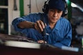 Car mechanic in uniform using ultrasonic sound tool to check irrecgular engine working part at garage and service station