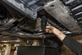 The car mechanic unscrews the diesel oil filter located in the oil pan, you can see the old oil flowing down in black. Royalty Free Stock Photo