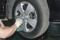 The car mechanic unscrews the wheel nuts with his hand