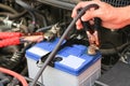 Car mechanic uses battery jumper cables charge a dead battery.