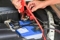 Car mechanic uses battery jumper cables charge a dead battery.