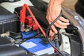 Car mechanic uses battery jumper cables charge a dead battery.