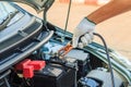 Car mechanic uses battery jumper cables to charge a dead batte Royalty Free Stock Photo