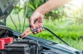 A car mechanic uses battery jumper cables to charge a dead battery