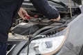 Car mechanic uses battery jumper cables to charge dead battery Royalty Free Stock Photo