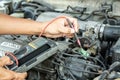 A car mechanic uses a meter to measure the electricity in the engine