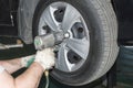 The car mechanic uses a pneumatic wrench to tighten the wheel nut Royalty Free Stock Photo