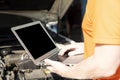 A car mechanic is using a laptop computer to check the engine operation Royalty Free Stock Photo