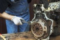 Car mechanic in work gloves unscrews the clutch from the engine block during repair in the workshop. Royalty Free Stock Photo