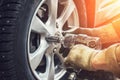 Car mechanic worker doing tire or wheel replacement with pneumatic wrench in garage of repair service station Royalty Free Stock Photo