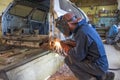 A car mechanic works angle grinder with a car body in a workshop. auto repair concept