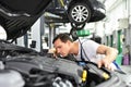 car mechanic in a workshop - engine repair and diagnosis on a vehicle