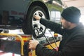 CAUCASIAN MECHANIC CHECKING THE WHEELS PRESION DURING A TUNE-UP Royalty Free Stock Photo