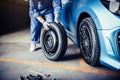 Car mechanics changing tire at auto repair shop garage. Transportation and Business working people concept. Automobile technician