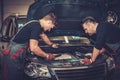 Car mechanics checking under hood in auto repair service. Royalty Free Stock Photo