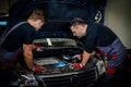 Car mechanics checking under hood in a workshop Royalty Free Stock Photo