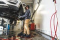 Car mechanics installing a new car wheel on a vehicle on a hoist in auto repair shop Royalty Free Stock Photo