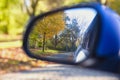 Car mirror Closeup with beautiful autumn landscape in reflection, on the road with the car on empty road blurred background Royalty Free Stock Photo