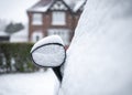 Car mirror parked on drive snowed in heap of snow settled on top house in background on residential street whole vehicle covered Royalty Free Stock Photo