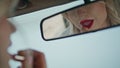 Car mirror reflecting beautiful woman applying red lipstick on lips close up. Royalty Free Stock Photo